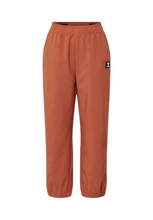 Pantalones jogger con cintura y tobillos elásticos de color oxido con una pequeña parche de logo en blanco y negro en el muslo derecho.