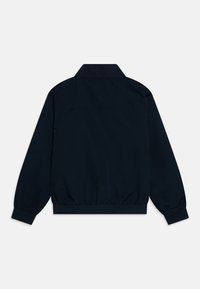 Giacca leggera blu navy con colletto alzato, polsini ed elastico in vita. Presenta una texture di tessuto liscia e un design minimalista.
