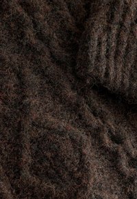 Dunkelbrauner gestrickter Pulloverstoff mit einer weichen, strukturierten Oberfläche. Verfügt über komplexe Stiche mit feinen Farb- und Dickevariationen.