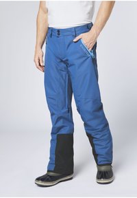 Blue waterproof ski pants with black ankle cuffs, zipper pockets, and a textured fabric. Features a slim fit and reinforced seams.