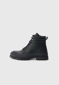 Sorte lær ankle boots med en grov sål, med runde snørebånd, metalløyer og en polstret krage for ekstra komfort.