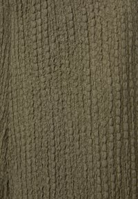 Tissu vert olive avec un motif en relief texturé de lignes verticales irrégulières et de petites formes ovales.