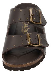 Brown leather sandal featuring two adjustable straps with brass buckles, stud detailing, and a textured footbed on a textured sole.