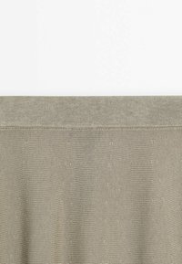 Tissu tricoté beige avec un détail d'ourlet plié le long du bord supérieur sur fond blanc.