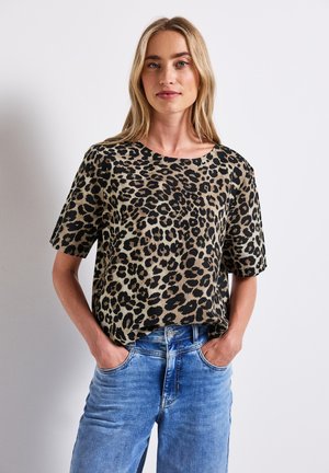 Leopard print short-sleeve top in beige and black, featuring a relaxed fit and round neckline, paired with blue denim jeans.