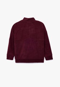 Burgundy fleece-paita, jossa on korkea kaulus, pudotetut olkapäät ja ribattu hihansuu sekä helma. Sileä pinta, jossa on tasainen, yksivärinen sävy.