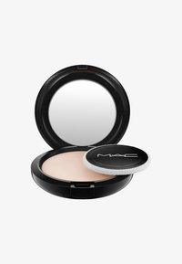 Compactpoeder in een zwarte ronde verpakking met een spiegel; beige poeder binnenin en een ronde applicator met een witte rand.