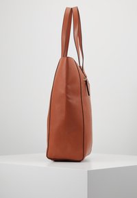 Bruine leren tas met een gestructureerd oppervlak, zijrits, lange hengsels en contrasterende zwarte trim, met een rechthoekige vorm.