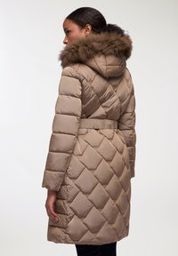 Giacca a vento beige con trapuntatura a rombi, cappuccio con bordo in pelliccia e vita con cintura. Materiale liscio con silhouette aderente.