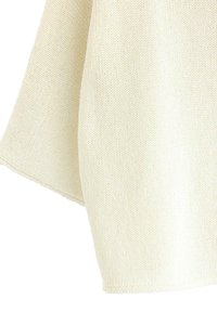 Lys beige strikket sweater med en løs pasform, der har en blød tekstur og synligt ribbet mønster langs kanterne.
