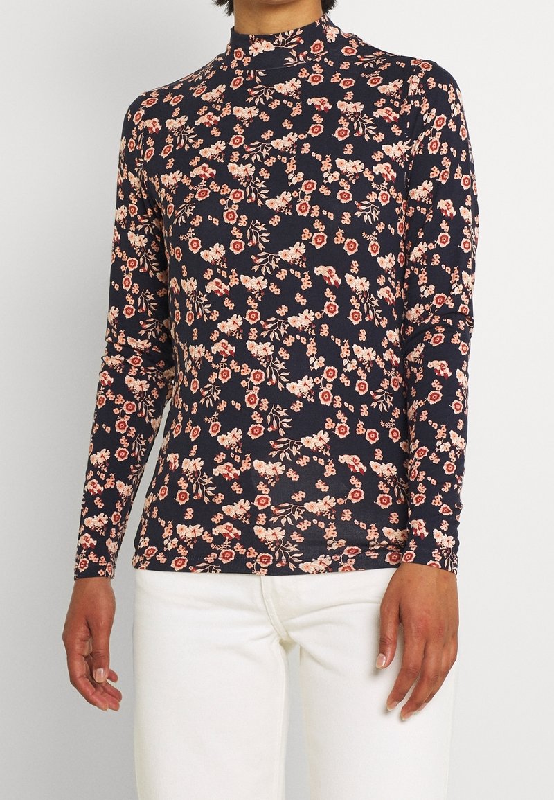 Långärmad polotröja i marinblått med ett blommönster som innehåller röda och vita blommor. Tillverkad av mjukt, elastiskt tyg. Fitted design.