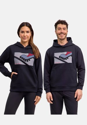 Mann und Frau tragen schwarze Kapuzenpullover mit grauer und roter Cleat-Grafik, stehen und blicken nach vorne vor weißem Hintergrund.