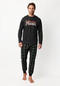 Camisa negra de manga larga con gráfico "FIESTA COMO UN ANIMAL". Pantalones de pijama a cuadros en verde, rojo y negro con puños elásticos.