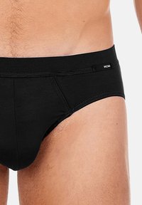 Schwarze Herrenunterhosen aus weichem Stoff, mit einer engen Passform, niedriger Taille und kontrastierendem Markenlogo an der Seite.
