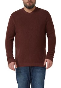 Brązowy, teksturowany sweter z okrągłym dekoltem i długimi rękawami, zestawiony z niebieskimi dżinsami.