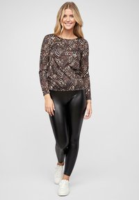 Langermet, tettsittende topp med brun og svart zebra print; kombinert med høyglans svarte leggings og hvite joggesko.