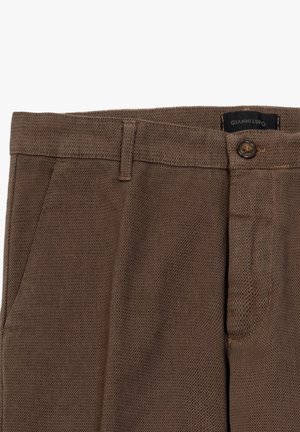 Pantaloni intrecciati marroni con chiusura a bottone, due tasche laterali e un tessuto testurizzato. Etichetta con la scritta "Gianni Lupo."