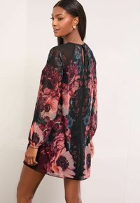 Rochie florală tip shift din material negru transparent, cu trandafiri mari în nuanțe de roz și burgund, mâneci lungi cu manșete elastice și decolteu în formă de cheie la spate.