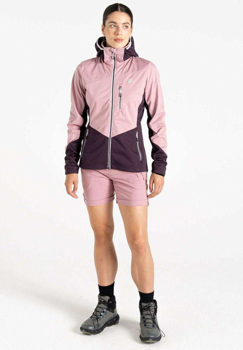 Leichte, zweifarbige Jacke in Pink und Dunkelpurpur mit einem Reißverschluss vorne, Kapuze und Reißverschlusstaschen, kombiniert mit pinken Shorts und grauen Wanderschuhen.