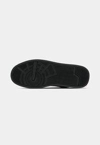 Talpa de cauciuc negru cu modele de striații circulare și în zigzag și cu logo-ul "Tommy Hilfiger" în centru.