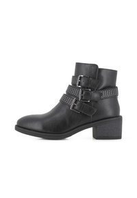 Botines de faux cuero negro con tres correas ajustables que cuentan con hebillas metálicas y tachuelas, tacón cuadrado de 3 pulgadas y punta redondeada.