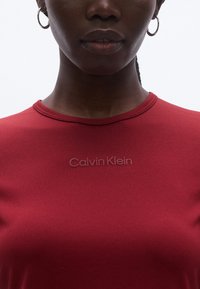 Piros, texturált póló kerek nyakkivágással, a mellkason finoman dombornyomott "Calvin Klein" logóval.