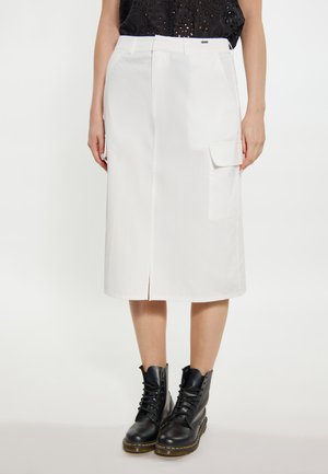 Witte knielange rok met een split aan de voorkant, zijzakken en een relaxte pasvorm. Gemaakt in combinatie met zwarte veterschoenen voor contrast. Gladde textuur.
