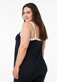 Zwarte tanktop met een ronde hals en lichtgekleurde bandjes, met een relaxte pasvorm en zachte stof. De achterkant is iets open.