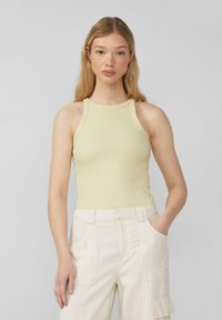 Lichtgele geribbelde tanktop met een hoge halslijn en zonder mouwen, gecombineerd met crèmekleurige, relaxte cargobroek met zijzakken.