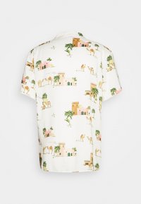 Camiseta de manga corta en tela blanca con estampado de escena del desierto con camellos y edificios en tonos rosas, verdes y terrosos.