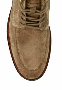 Beige nubuck laars met ronde neus, contrasterende bruin gestikte rand, vetersluiting en zilverkleurige vetertjes. Gladde structuur overal.