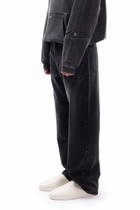 Svarte jeans med løs passform, med sidelåser med knapp, en falmet tekstur, og kombinert med lyse slip-on sko og en grå hettegenser.