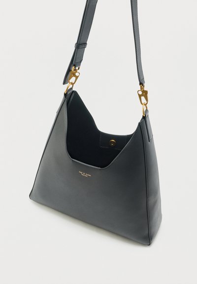 Μαύρη δερμάτινη τσάντα ώμου με κούμπωμα σε χρυσή απόχρωση, ρυθμιζόμενο λουρί και μαγνητικό κλείσιμο, σε κεκλιμένη όψη σε ανοιχτό φόντο.