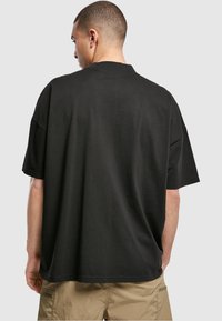 T-shirt noir oversize en coton, avec un col rond, des manches courtes et une coupe ample. Le tissu semble lisse et doux.