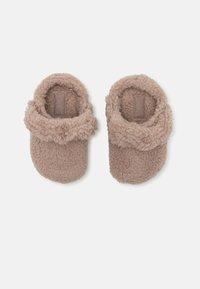 Tan fleece tofflor med en fluffig kant. Rundad form och mjuk textur. Har en subtil märkesetikett inuti. Inga synliga delar.