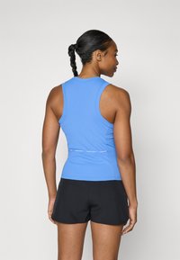 Blauwe sport tanktop met een slim fit ontwerp en racerback stijl, gecombineerd met zwarte shorts. Bevat een subtiele logo-opdruk nabij de taille.