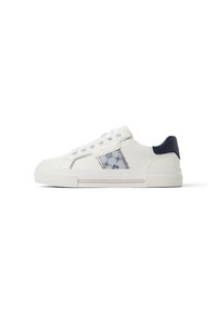 Zapatillas de lona blanca con parte superior texturizada, que cuentan con un acento azul en el talón y un panel lateral con un diseño. Suela de goma plana.