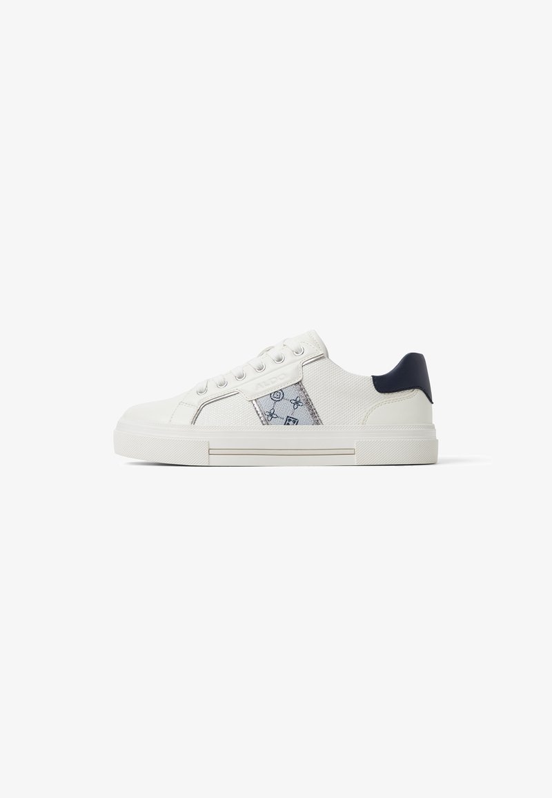 White canvas sneakers with a textured upper, featuring a blue accent on the heel, and a patterned side panel. Flat rubber sole.