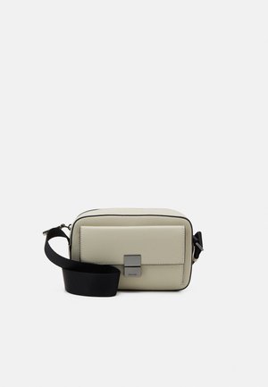 Borsa a tracolla rettangolare beige con tasca frontale e ampia tracolla nera regolabile su sfondo bianco.