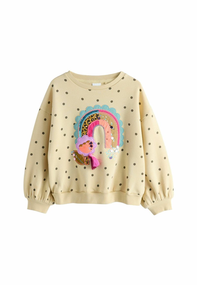 Gul sweater med polkaprikker og ballonærmer, prydet med et farverigt regnbue-design, der inkluderer teksturer og palietter.