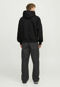Black hooded sweatshirt with a relaxed fit, made of soft material. Paired with dark gray cargo pants featuring multiple pockets.