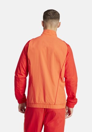 Veste pour hommes en orange vif et rouge. Tissu léger avec une texture lisse, col zippé, poignets côtelés et taille élastique.