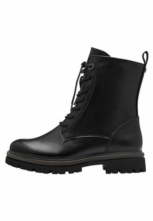 Botte chelsea en cuir noir à lacets avec semelle robuste et languette au talon, conçue pour une utilisation en extérieur et décontractée.
