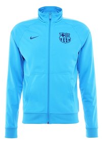 Helleblaue Full-Zip-Jacke mit hohem Kragen, Nike-Logo auf der rechten Brust, FC Barcelona-Wappen auf der linken Brust und vorderen Handtaschen.