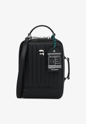 Czarna mini torba na twardym spodzie od Karl Lagerfeld z wytłoczonym logo, górnym uchwytem, odpinanym paskiem, ikoną okularów przeciwsłonecznych oraz przypiętą etykietą podróżną.