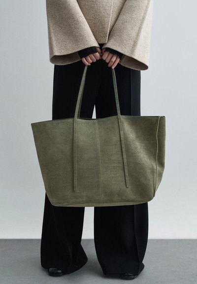 Oliemgroene suÃ¨detote met twee lange hengsels, rechthoekige vorm en zichtbare stiksel details, gepresenteerd tegen een neutrale achtergrond.