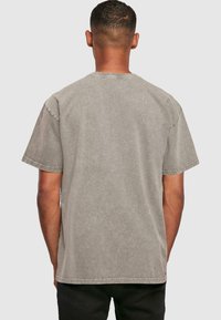 Camiseta gris de manga corta con un ajuste relajado. Tejido suave y texturado, costuras visibles en el cuello y las mangas, apariencia ligeramente descolorida.