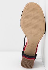 Podeszwa buta z teksturowanej, antypoślizgowej brązowej gumy, z czerwono-granatowym materiałowym wierzchem. Rozmiar 37 oznaczony na podeszwie.