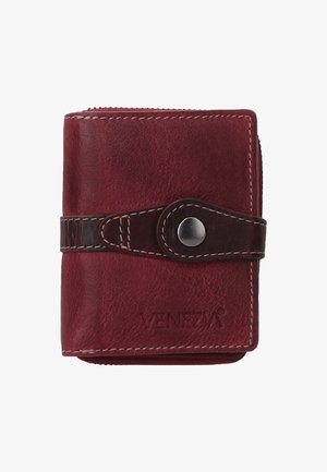 Portefeuille en cuir rouge avec fermeture éclair, sécurisé par une sangle brun foncé et un bouton-pression argenté, arborant le nom de la marque embossé sur le devant.
