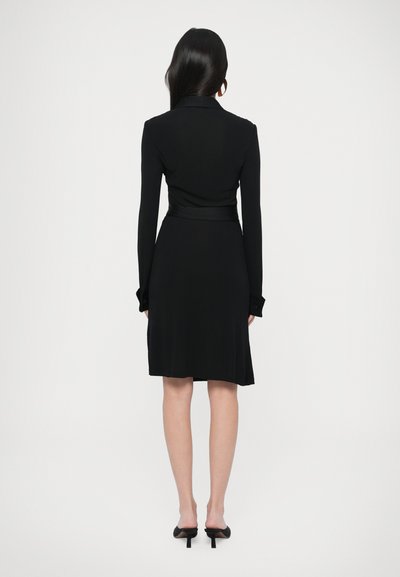 Μαύρο φόρεμα μακρυμάνικο με εφαρμοστό πάνω μέρος, φαρδύ φουστάνι και ζώνη στη μέση. Κατασκευασμένο από λείο ύφασμα, με μανσέτες με κουμπιά.